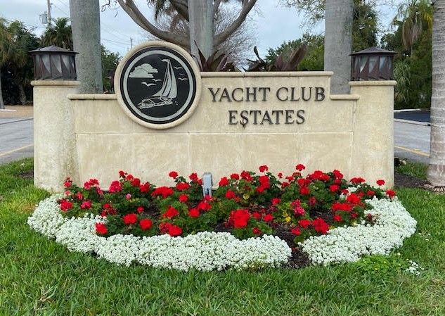 yacht club estates yard sign with red flowers